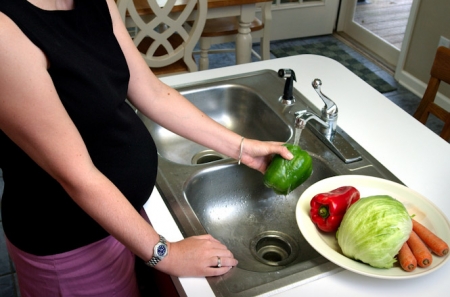 Una mujer embarazada lava las verduras antes de cocinar (UGR)