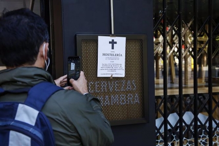 Un joven fotografía una esquela puesta en un bar de una de las calles comerciales de la ciudad de Granada (ÁLEX CÁMARA / EUROPA PRESS) 