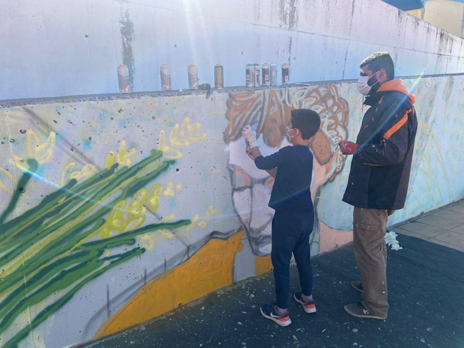 el graffitero de La Zubia Alc13 junto a los escolares del  CEIP Al Zawiya que están realizando el graffiti (AYTO. LA ZUBIA)