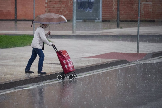 Una mujer regresa de hacer la compra en plena lluvia (EDUARDO SANZ / EUROPA PRESS) 