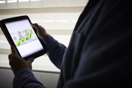 Un hombre sujeta una tablet con un gráfico (JESÚS HELLÍN / EUROPA PRESS)