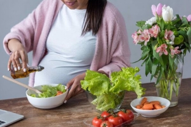 Una mujer embarazada aliña con aceite de oliva una ensalada, en imagen de recurso (FUNDACIÓN DESCUBRE)