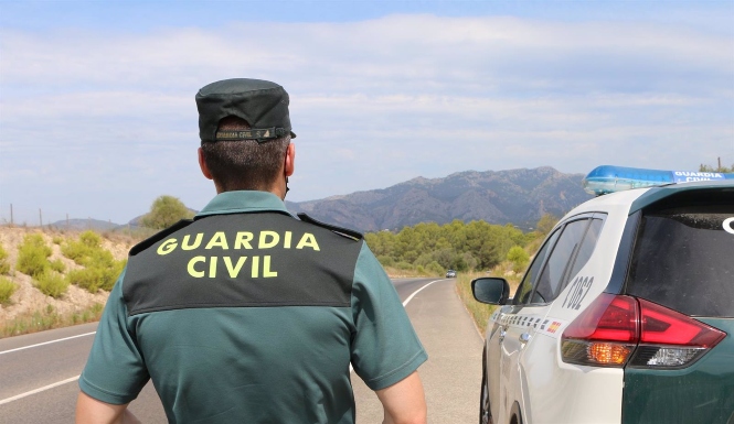 Un agente de la Guardia Civil junto a un vehículo en una carretera (GUARDIA CIVIL)