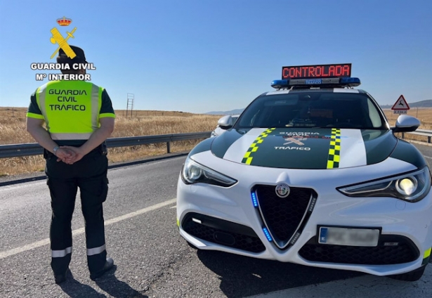 Un agente de la Guardia Civil de Tráfico junto a su vehículo en una carretera. Archivo (GUARDIA CIVIL)