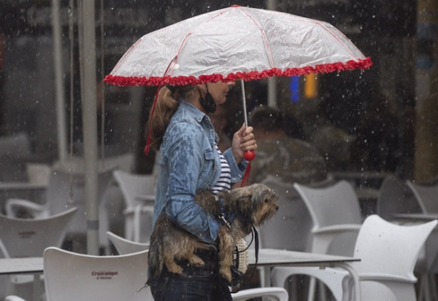 Una mujer lleva a su perro en brazos bajo una tormenta, archivo (MARÍA JOSÉ LÓPEZ - EUROPA PRESS)