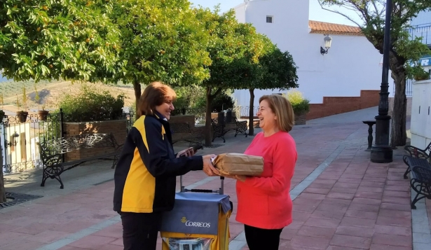 Cartera atiende a una usuaria en la calle de un pueblo (CORREOS)