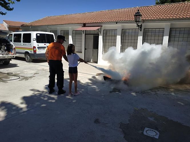 Un voluntario de Protección Civil enseña a una niña a apagar un fuego (AYTO. VEGAS DEL GENIL)
