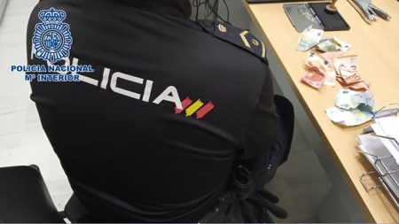 Un Policía Nacional junto al dinero recuperado (POLICÍA NACIONAL) 