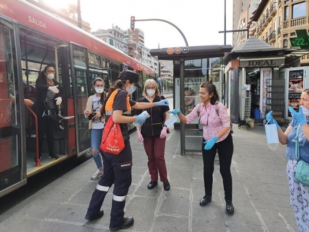 Una voluntaria de Protección Civil reparte mascarillas en una parada de autobús (SUBDELEGACIÓN) 