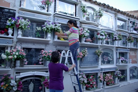 Una familia pone flores en un nicho del cementerio de Montefrio (AYTO. MONTEFRIO)