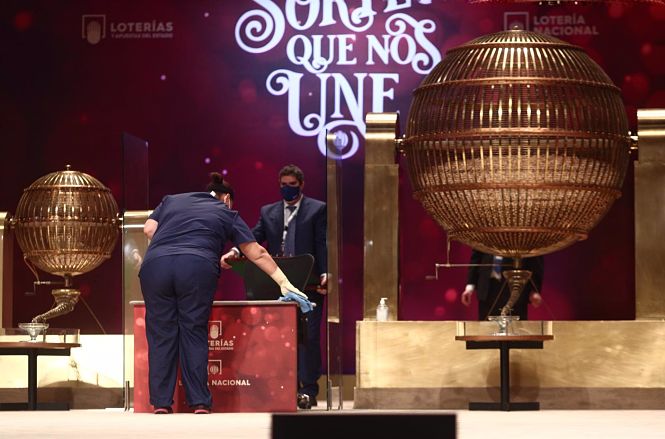 Una empleada limpia la mesa del Sorteo para que se cumplan todas las medidas de higiene durante la celebración del Sorteo (EDUARDO PARRA / EUROPA PRESS)