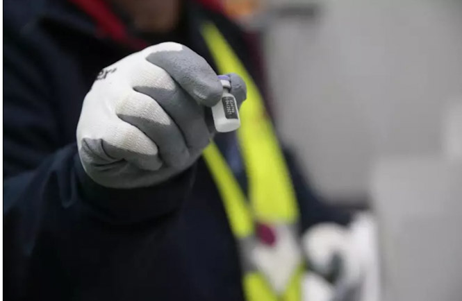 Una persona de los laboratorios que han desarrollado las vacunas, Pfizer y BioNtech muestra una dosis de la vacuna. (MONCLOA)