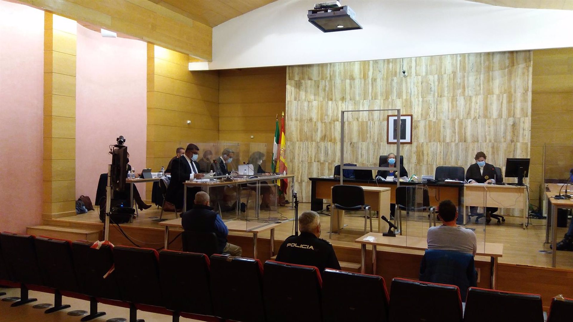 Juicio al supuesto autor del asesinato y enterramiento de su mujer en Guadix, de espaldas, el primero a la izquierda del policía en la imagen (EUROPA PRESS) 