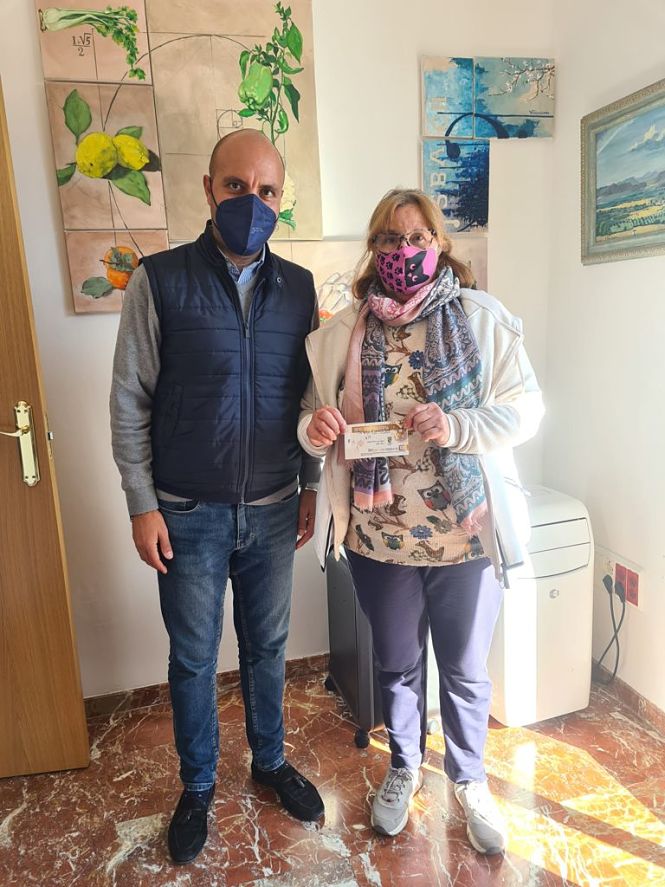 el alcalde de Otura, Nazario Montes, entrega un bono de compra a una vecina del municipio durante la pasada campaña de Navidad(AYTO. OTURA) 