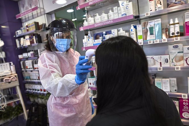 Una farmacéutica toma la temperatura a una mujer antes de realizarle un test de antígenos (JESÚS HELLÍN - EUROPA PRESS) 