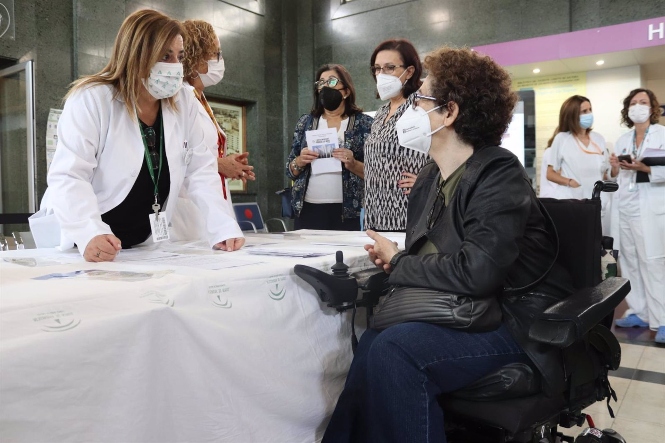 Una cuidadora se acerca a una mesa informativa (HOSPITAL VIRGEN DE LAS NIEVES) 
