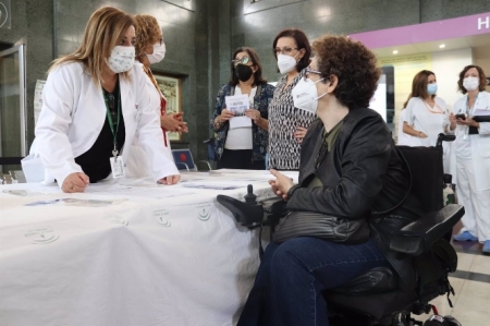Una cuidadora se acerca a una mesa informativa (HOSPITAL VIRGEN DE LAS NIEVES) 