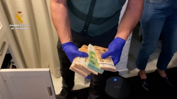 Un agente con el dinero incautado en uno de los registros (GUARDIA CIVIL) Un agente con el dinero incautado en uno de los registros (GUARDIA CIVIL)