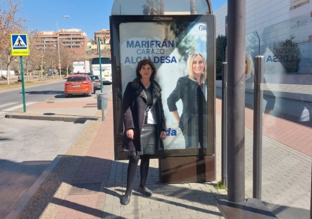 Elisa Cabrerizo, de UP en Granada, ante una marquesina con la imagen de Marifrán Carazo, del PP (UP) 