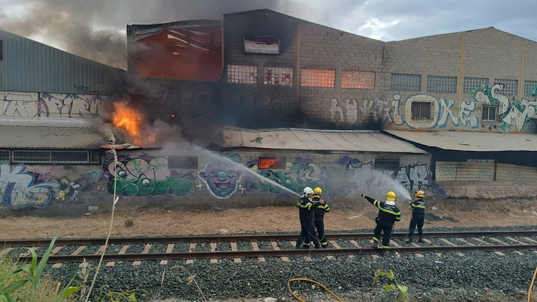 Imagen cedida por Protección Civil de Peligros (Granada) en la que se puede ver a los bomberos trabajando en las tareas de extinción del incendio declarado en una nave industrial de la localidad (PROTECCIÓN CIVIL PELIGROS)