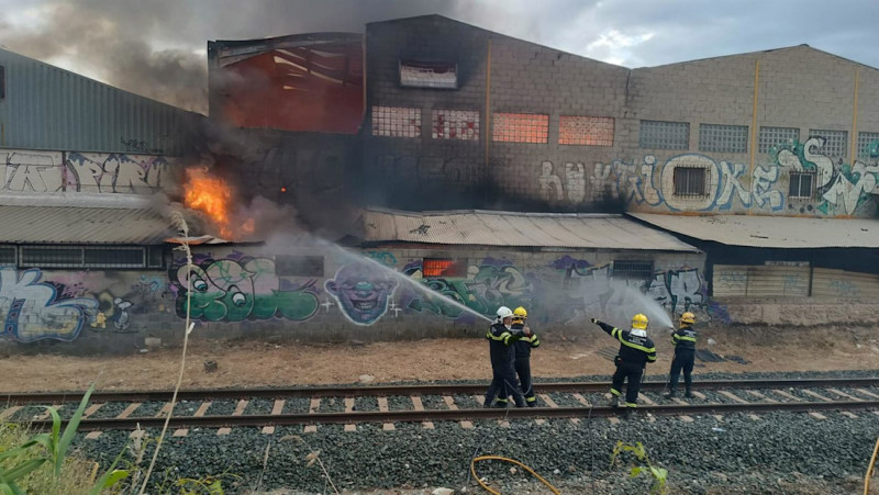 Imagen cedida por Protección Civil de Peligros (Granada) en la que se puede ver a los bomberos trabajando en las tareas de extinción del incendio declarado en una nave industrial de la localidad (PROTECCIÓN CIVIL PELIGROS)